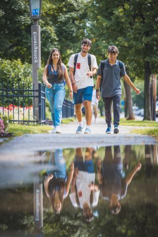 Three students walking down sidewalk